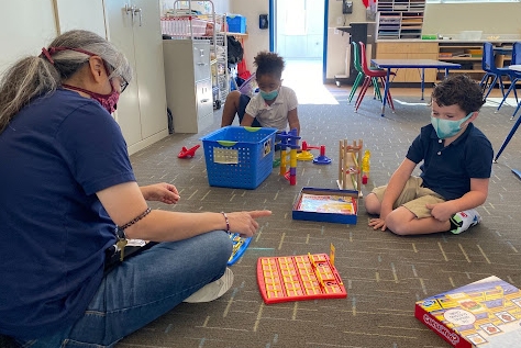 At BASE, we’re a family. We cook together, craft, exercise, and play lots of games. Here’s Miss Tina playing a riveting game of Guess Who with our kindergarteners.